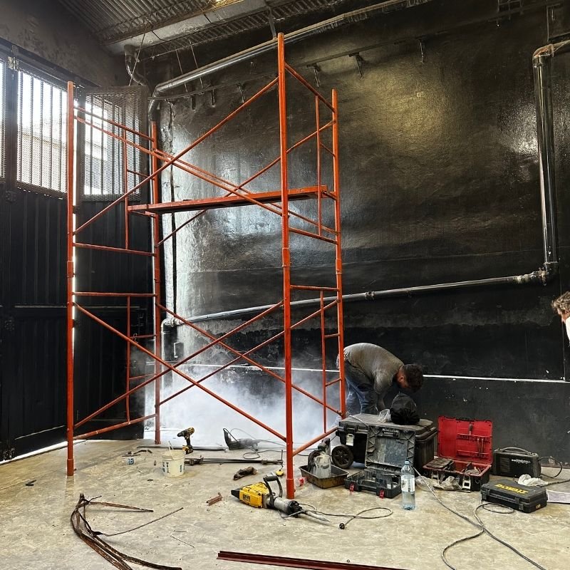 Cambio total de guía inferior en portón curvo-corredizo. Sustitución completa de la guía inferior de un portón curvo-corredizo, deteriorada por el óxido. Se fabricó e instaló una nueva guía en hierro ángulo de 1 1/4'' x 1/8'' y planchuela de 3/4'' x 1/8''. El piso fue perforado y canalizado, fijando la guía con tacurú y cemento. Trabajo realizado por HERREELEC.